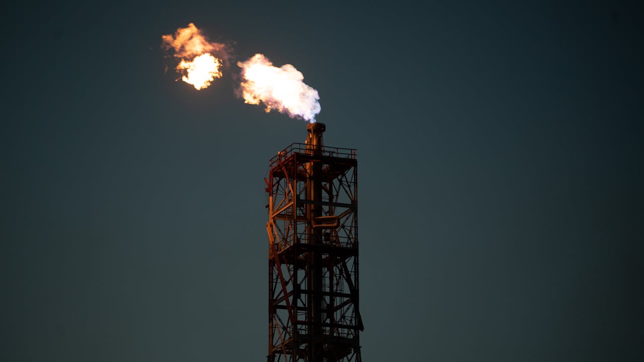 A towering industrial chimney with a dramatic flame against a dark sky in Salina Cruz, Mexico.
